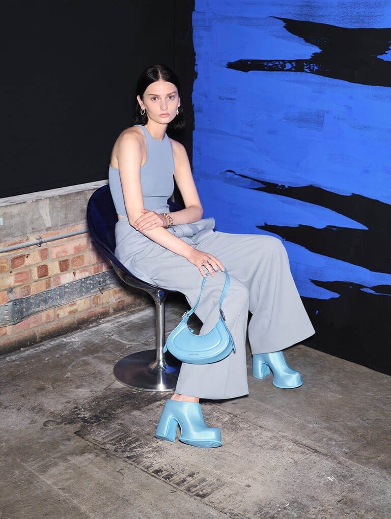 Women’s Pixie Platform Mules in blue; Petra Curved Shoulder Bag in blue; Sculptural Cuff Bracelet in silver; Star Crystal Mismatch Drop Earrings in gold; Double Chain Bracelet in silver and gold; Star Crystal Ring in gold; Criss Cross Ring in silver, Allegro Sculptural Ring in silver - CHARLES & KEITH