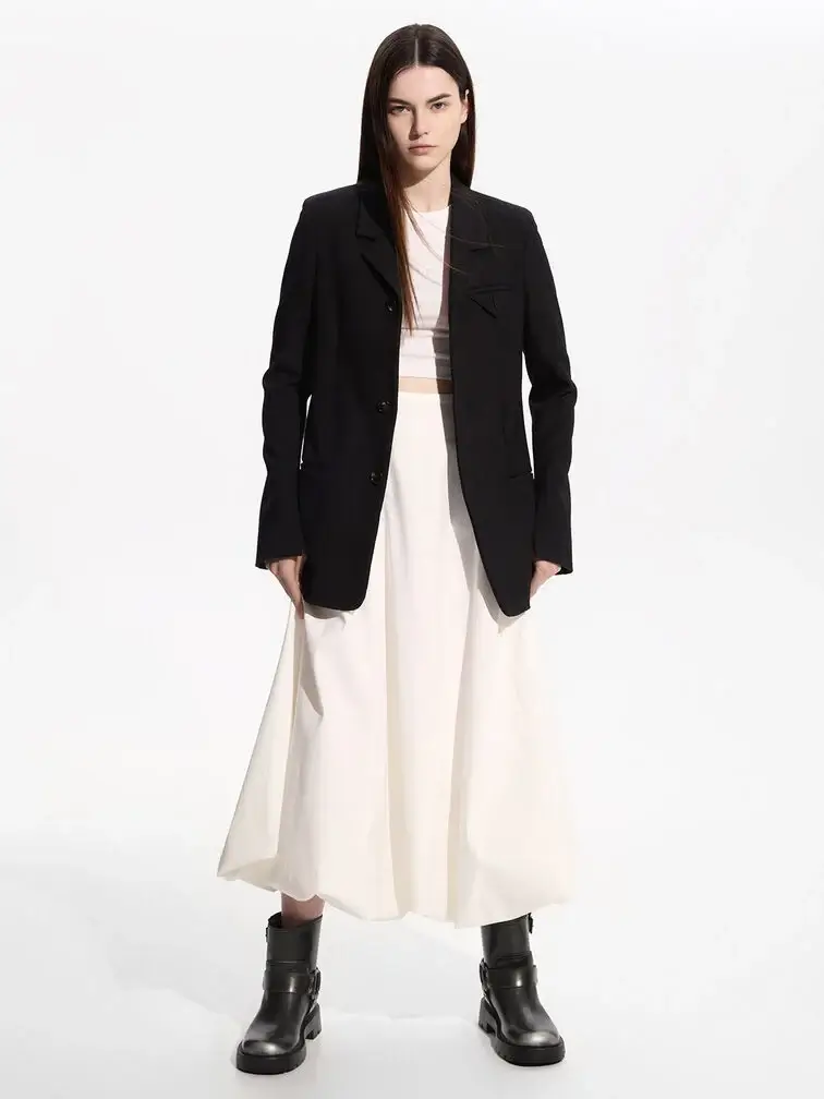 Chunky black ankle boots styled with a matching blazer layered over a white dress.