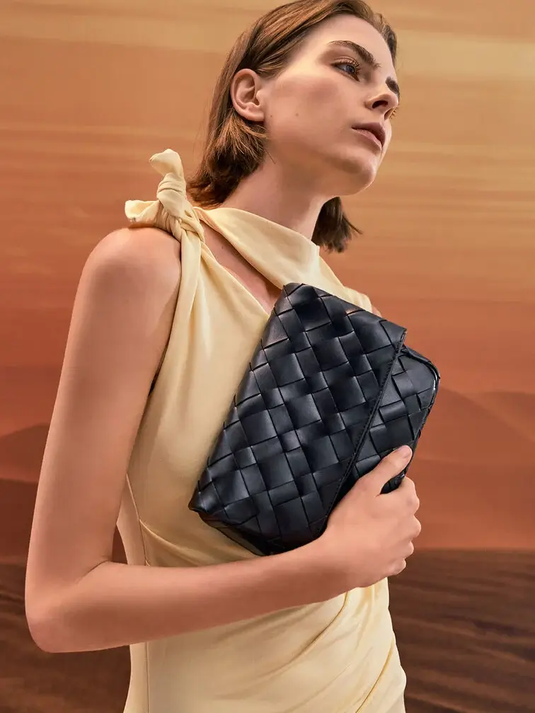 A butter yellow dress styled with a black woven clutch for a classic spring wedding guest look. 