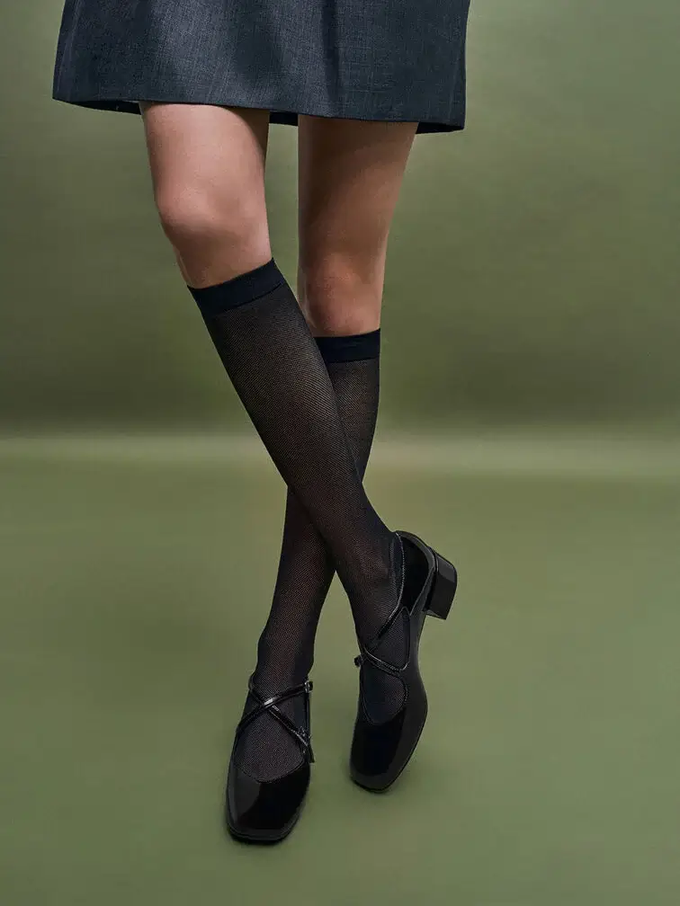 Black patent Mary Janes paired with sheer black knee-high socks
