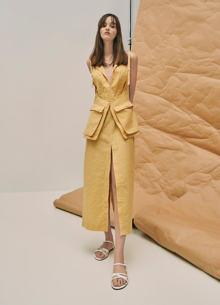 A model wearing a utilitarian dress with criss-cross ankle strap flats