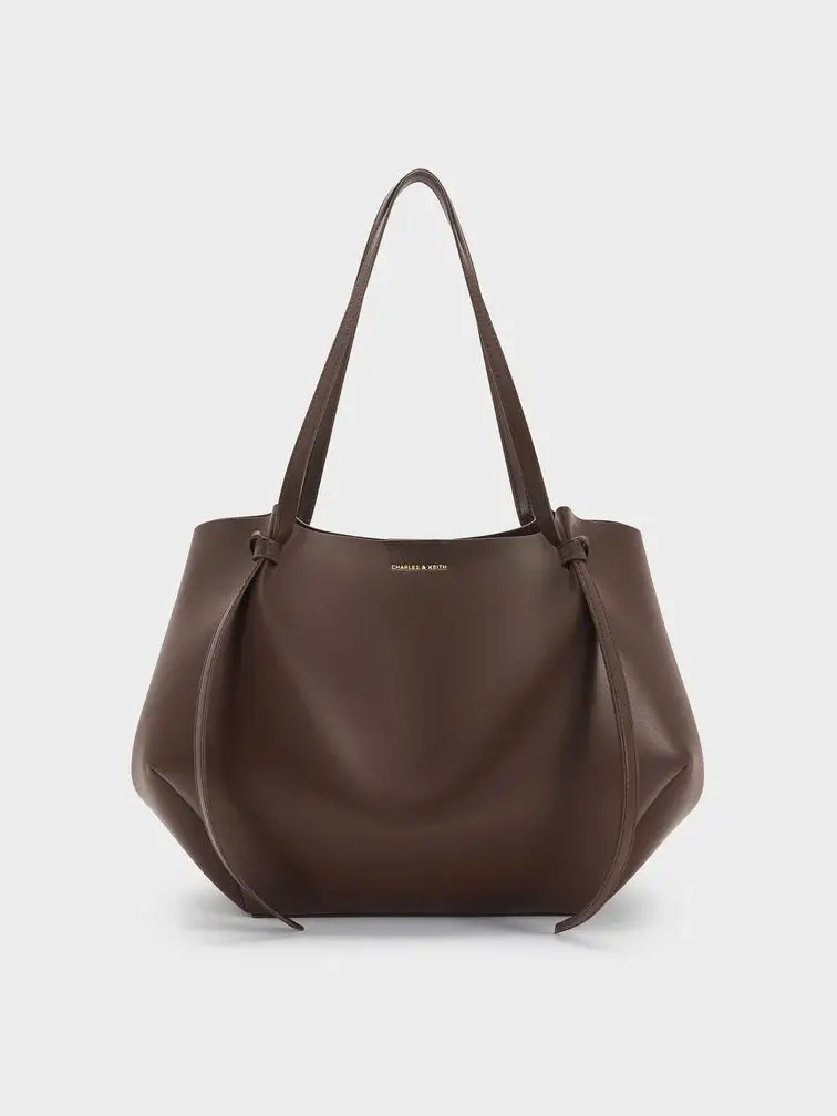 The XL Calla tote bag in espresso brown with the side magnetic clasps folded in to create a geometric-like shape