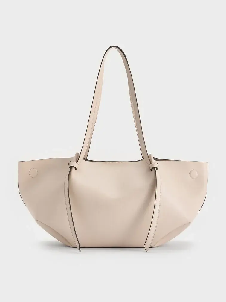  The Calla tote bag in oat with the side magnetic clasps folded out creates a wider and slouchier shape