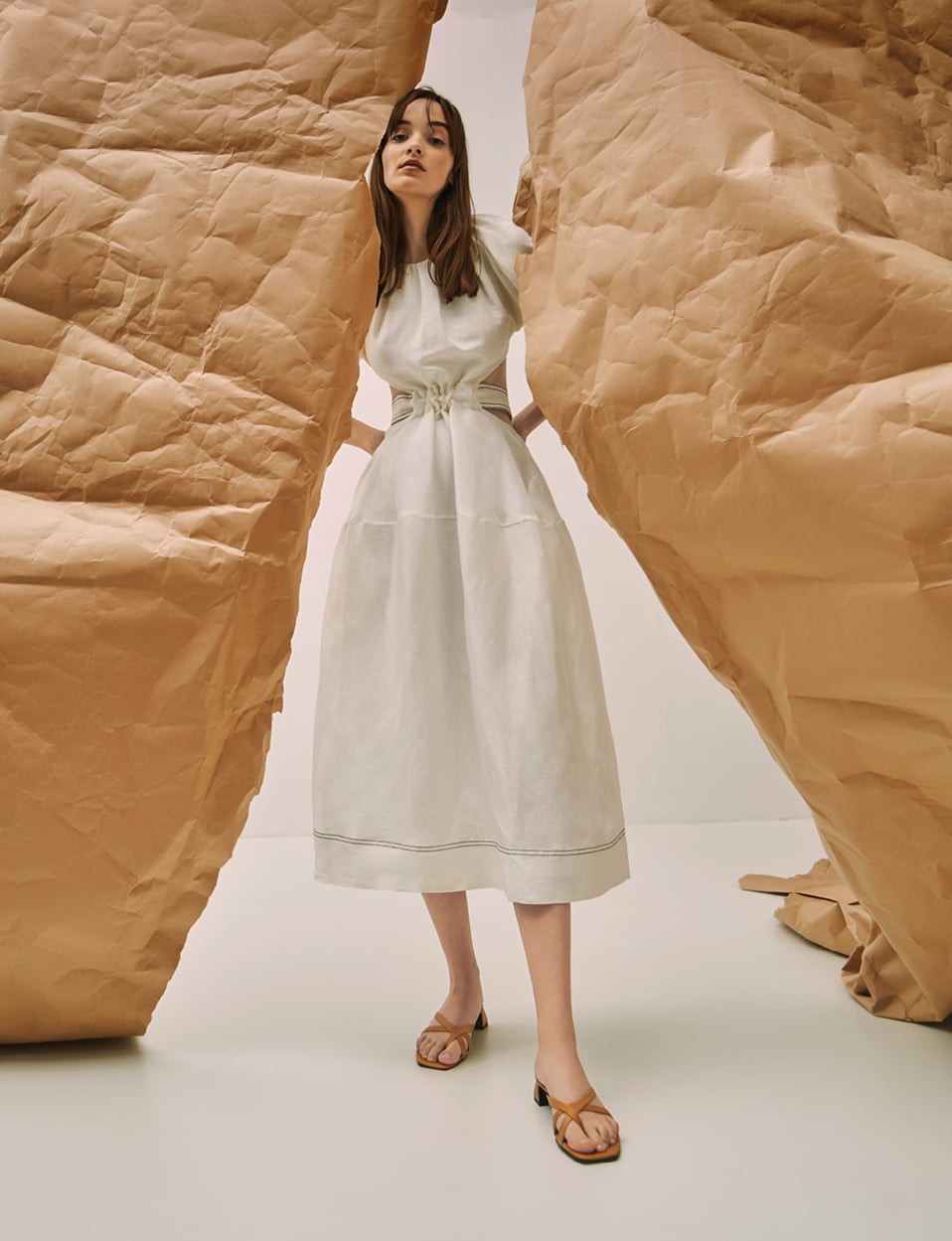 A model wearing a white maxi dress with strappy toe loop heeled sandals