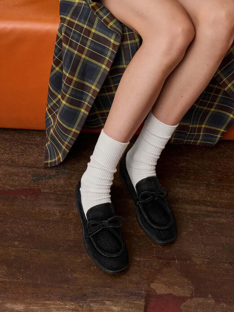  Black velvet bow loafers styled with white crew socks.